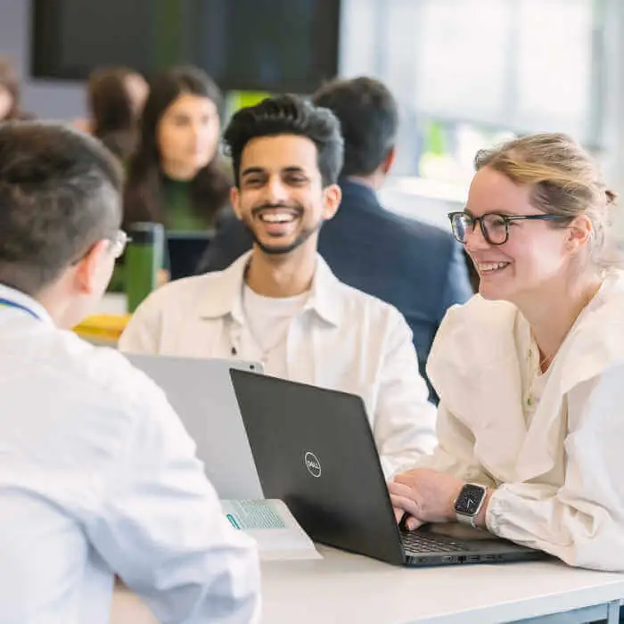 group of students sitting at a table with a laptop