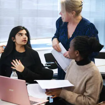 two female law students talking with female law academic with laptops on the table