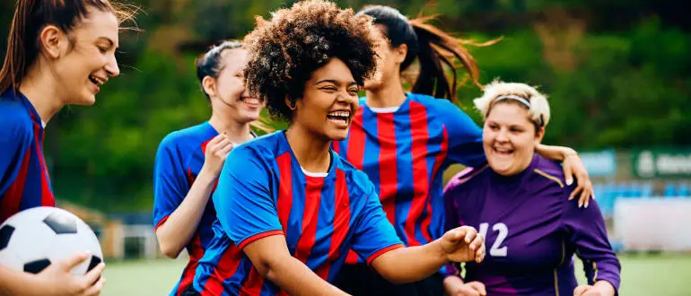 Women football players in blue and red jerseys on the field.